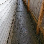 A sidewalk with concrete and wood on the side.